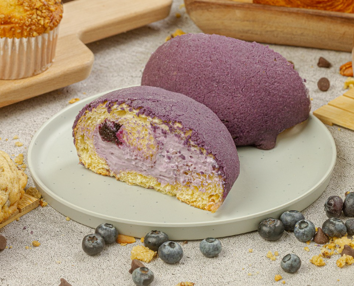 Conchita de Tagers partida a la mitad, rellena de crema, con moras azules alrededor