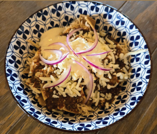 Chilaquiles con queso gratinado y cebolla morada en un plato de talavera