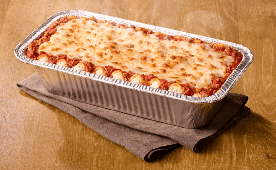 Bandeja de lasagna gratinada con salsa de tomate sobre una mesa de madera