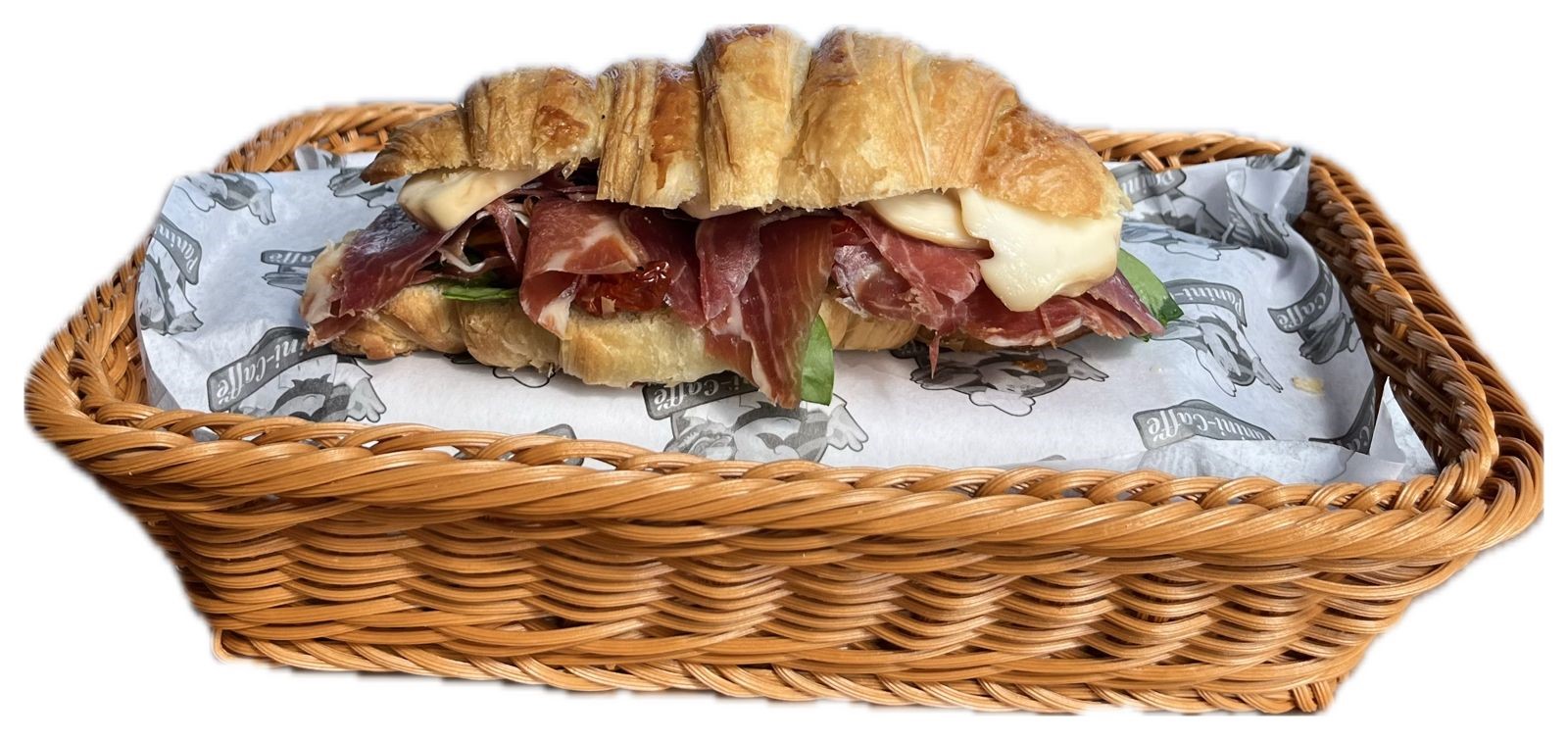 Croissant relleno de prosciutto, queso y arúgula servido en canasta de mimbre