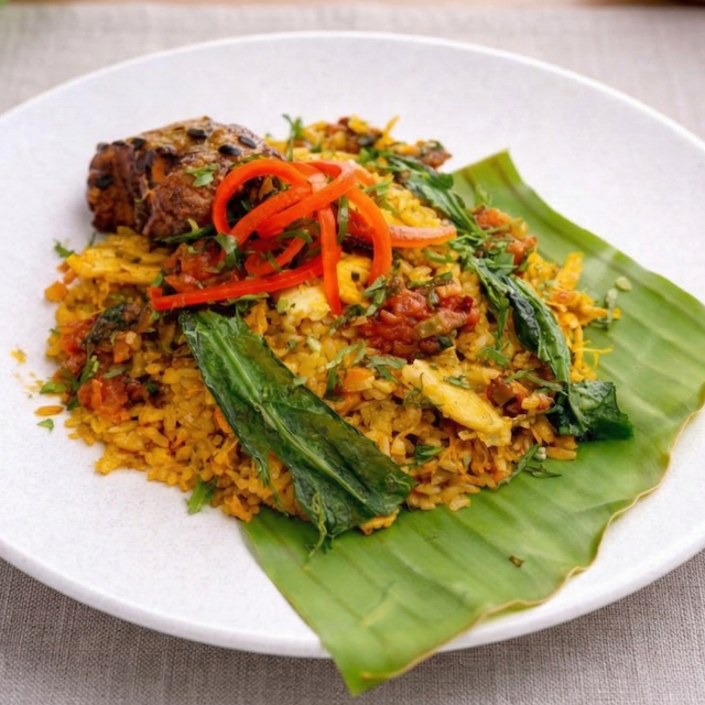 Arroz con pollo amarillo servido sobre hoja de plátano
