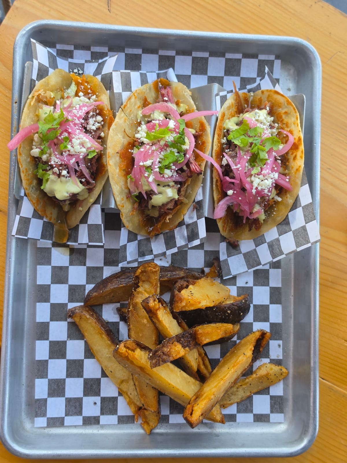 Tres tacos de barbacoa con cebolla encurtida, cilantro y queso Cotija, con papas gajo