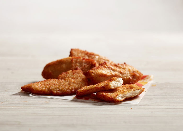 Tiras de pollo doradas con cobertura crujiente sobre papel