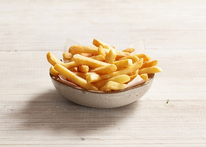 Papas fritas doradas en un bowl sobre una mesa clara