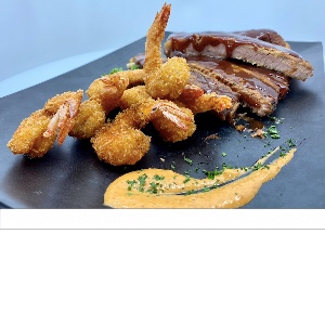 Plato mar y tierra con costillas en salsa y camarones apanados sobre pizarra